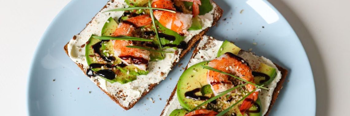Delicious shrimp avocado toast with cream cheese on rye bread, perfect for brunch.